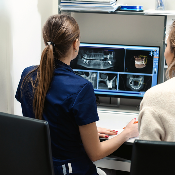 Female dentist looking at 3D images of mouth and jaw