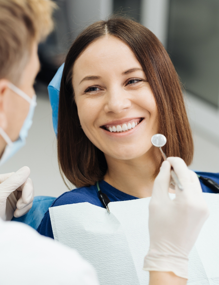 Woman in dental chair leaning back and smiling