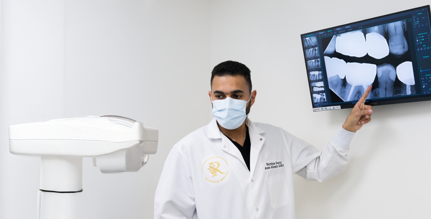Dentist in Raynham pointing to X ray of teeth