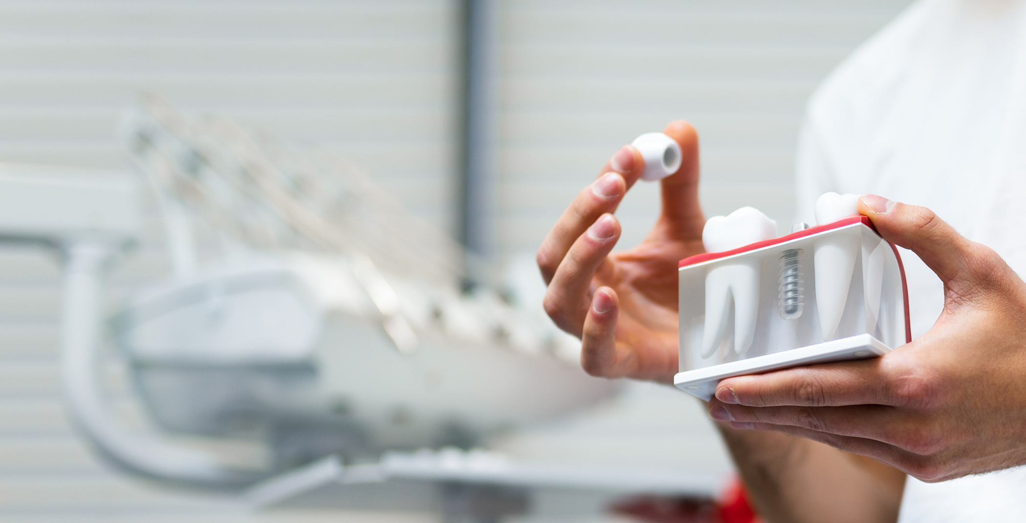 Hands holding crown and model of dental implant in Raynham