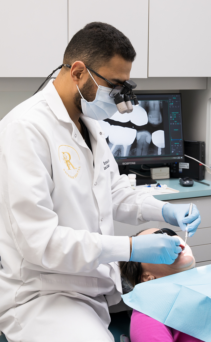 Dentist with magnifying glasses treating a patient