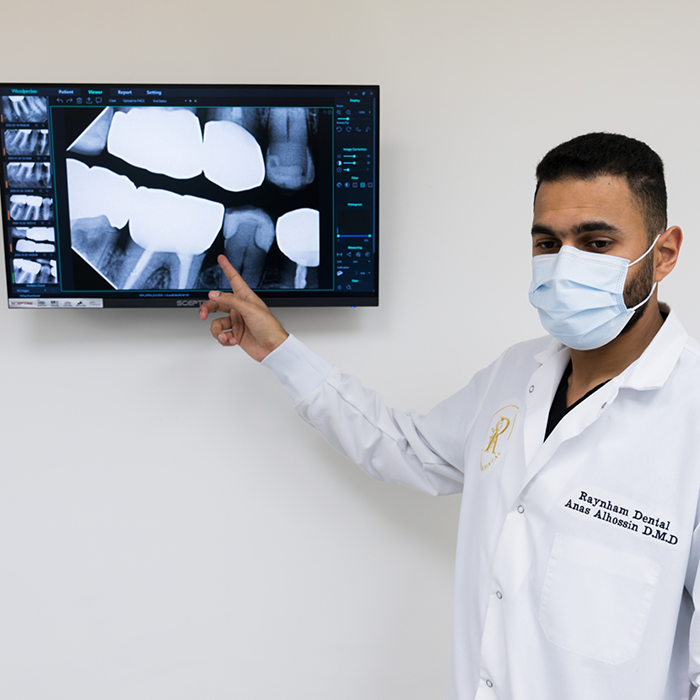 Dentist pointing to monitor with dental X-rays