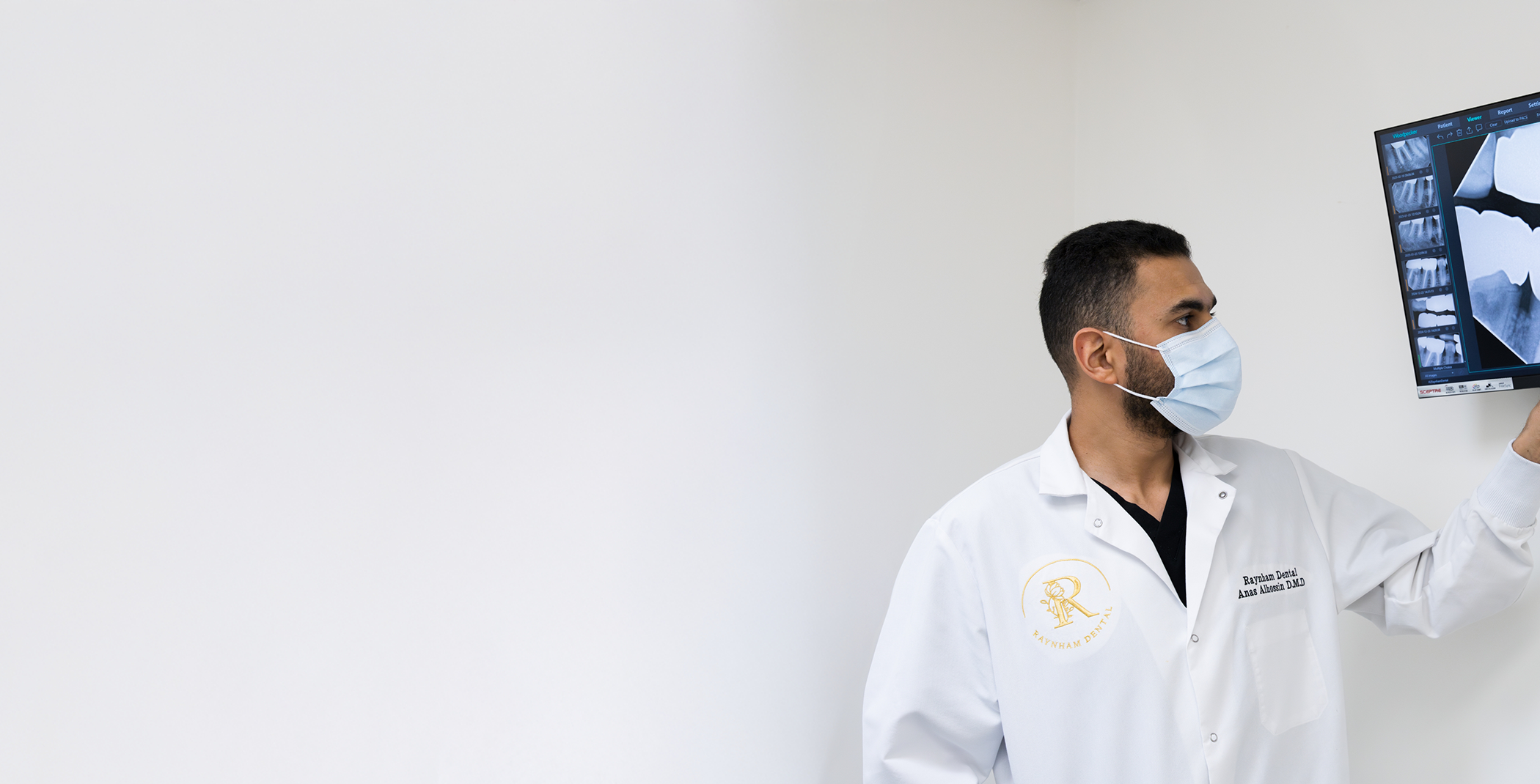 Dentist in Raynham wearing mask and looking at dental X-ray