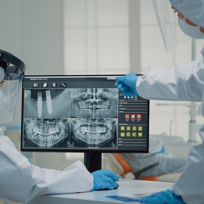 Dentist looking at multiple X-rays on computer monitor