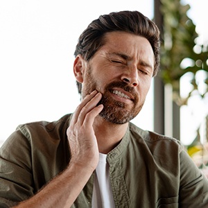 Man with beard rubbing jaw in pain