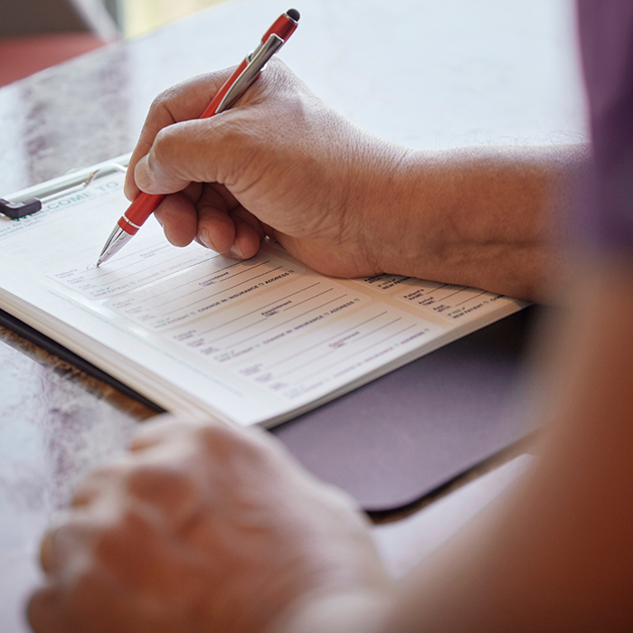 Filling out form on clipboard with a pen