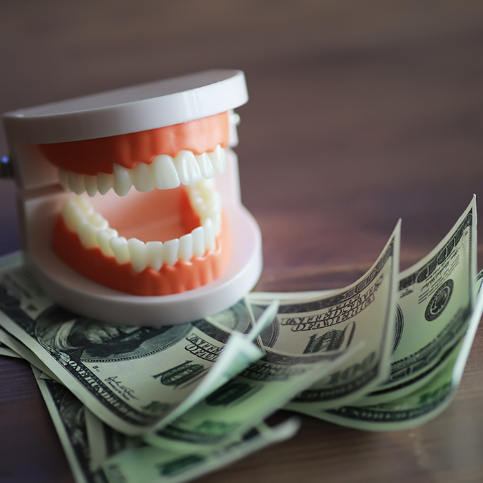 Dentures sitting on top of stack of hundred dollar bills