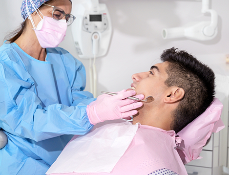 Male dental patient in pink shirt looking up at dentist