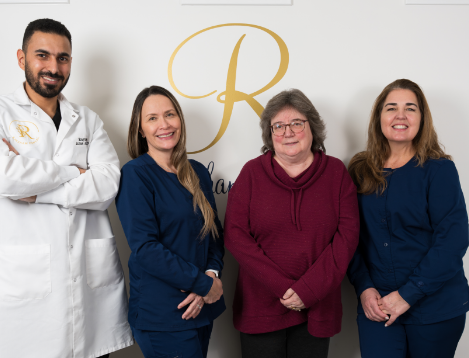 Dental team members standing in front of wall and smiling