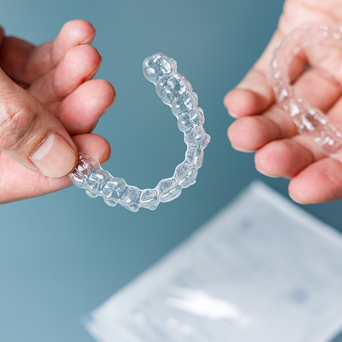 Hands holding multiple Invisalign aligners