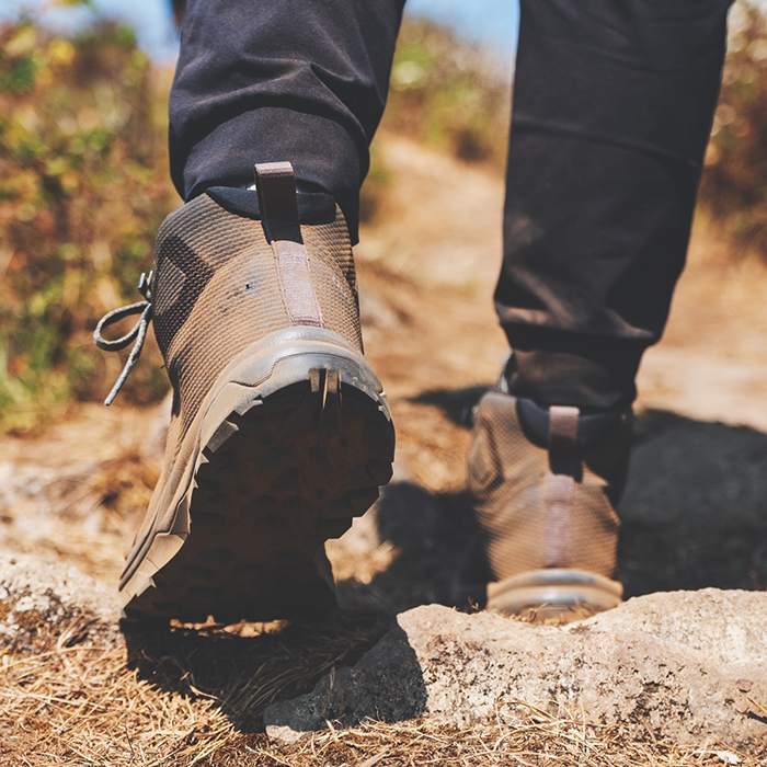 Close-up of boots while hiking down trail