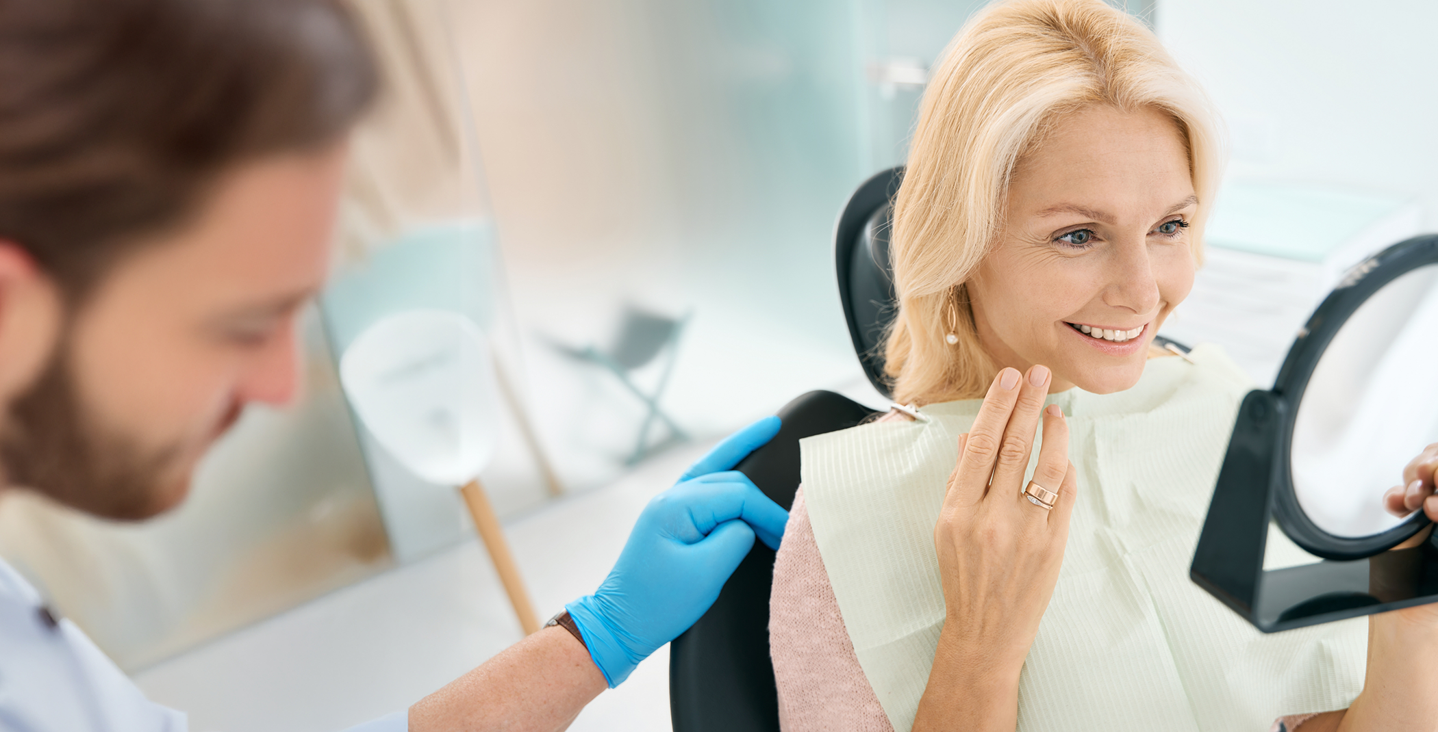 Senior woman checking restored smile in mirror