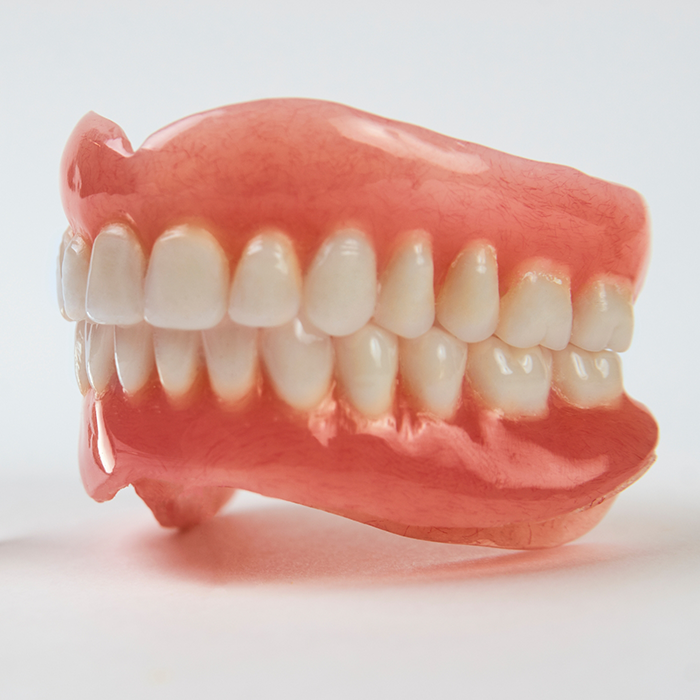 Close-up of full dentures sitting on white surface
