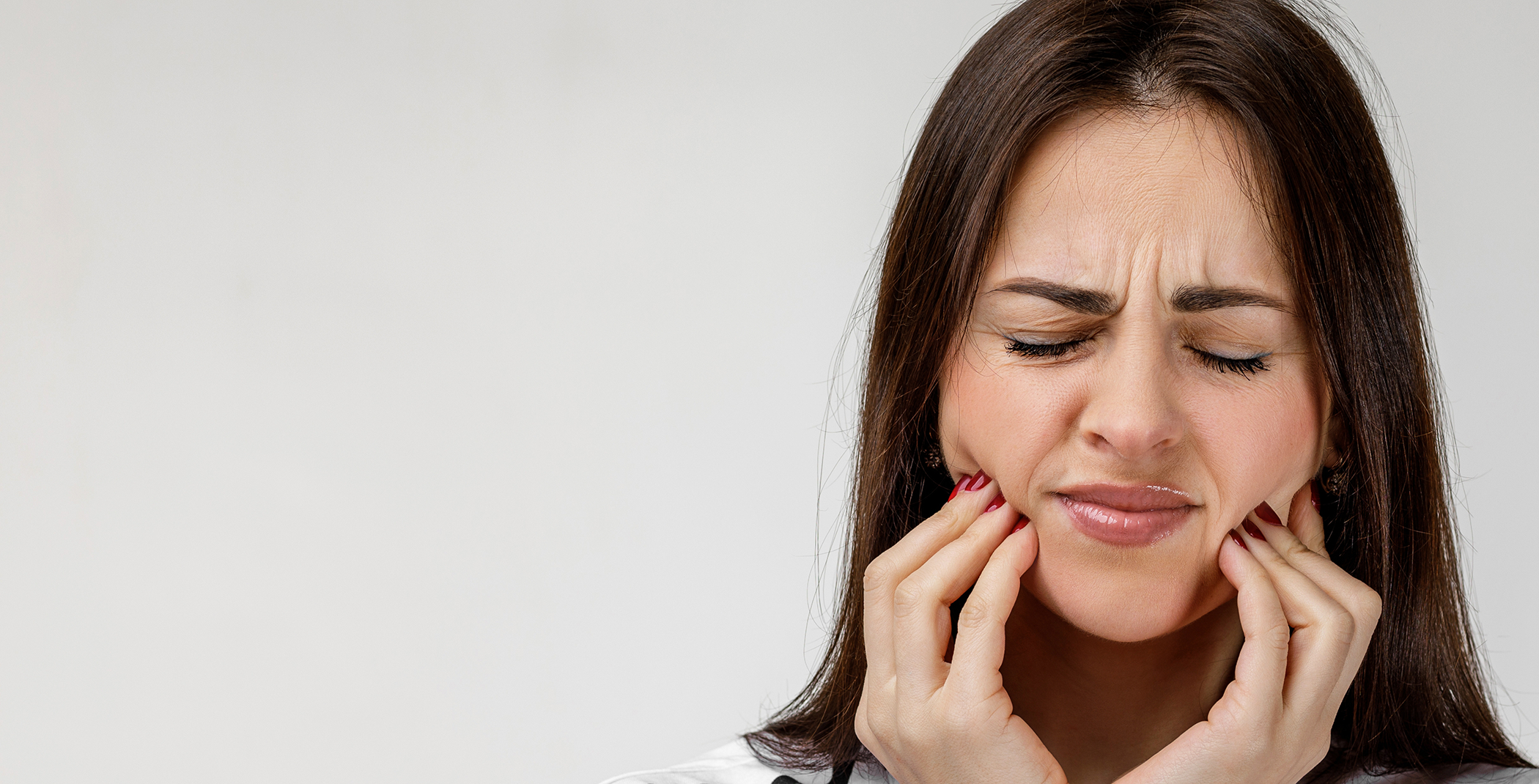 Woman rubbing both sides of her jaw in pain
