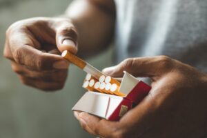 Person getting a cigarette out of a carton