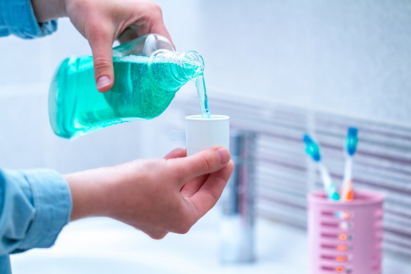 A man pouring mouthwash into a cup